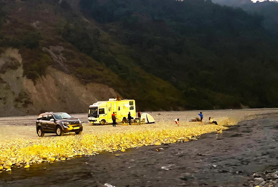 Riverside camping and activity area near Rishikesh surrounded by hills